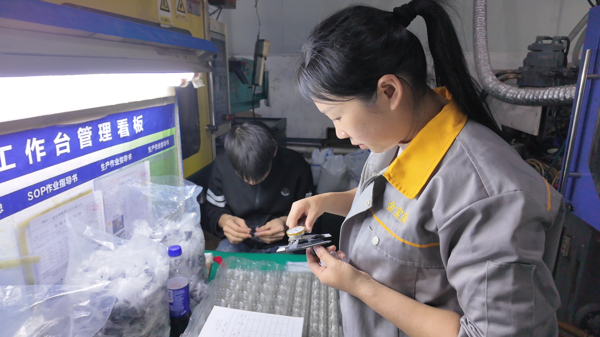 QC technician performing dimensional inspection on an injection molded part at JBRplas Shenzhen — ISO 9001 certified quality control